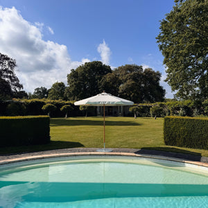 Cream parasol next to a pool 